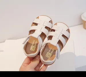 Primer plano de sandalias blancas tejidas con punta cerrada para niños con suelas blandas