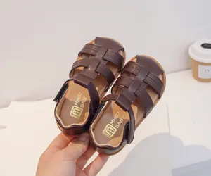 Detalle de sandalias trenzadas marrones para bebé con suela blanda y costuras finas.