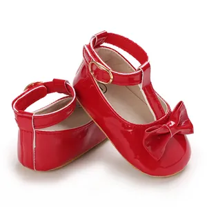 Detailansicht glänzend roter Baby-Lauflernschuhe mit dekorativer Schleife und T-Riemen.