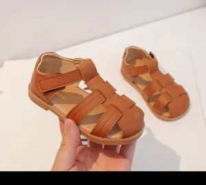 Primer plano de sandalias tejidas para niños en color marrón con suela blanda