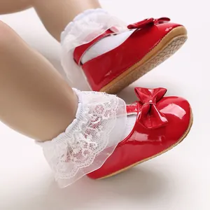 Nahaufnahme von roten Baby-Lauflernschuhen aus Lackleder mit Schleife und Spitze
