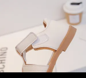 Detalle de sandalias blancas para niños pequeños con cierre de velcro y suela marrón