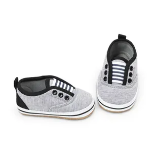 Detail of grey infant walking shoes with striped elastic laces and fabric upper