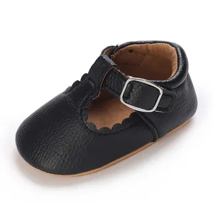 Close-up of black baby Mary Jane shoes with scalloped edges and silver buckle detail