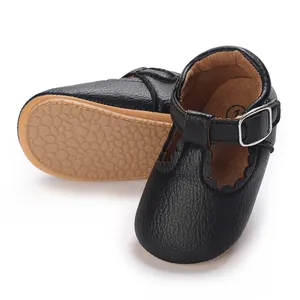 Detail view of black baby walking shoes with scalloped trim and non-slip rubber sole