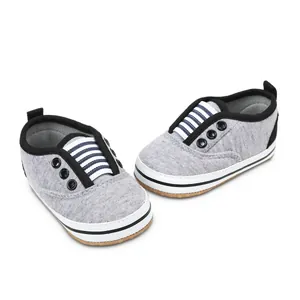 Macro view of grey baby walking shoes featuring soft anti-slip soles and stripes.