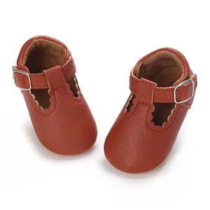 Close-up of brown leather baby pre-walker shoes with scalloped edges and T-strap