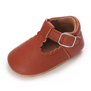 Detailed view of brown leather baby walking shoe with scalloped edges and buckle