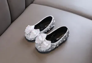 Detail von silbernen glitzernden Mädchen Prinzessinnenschuhen mit weißen Schleifen