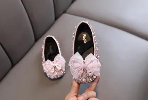Detail von rosa glitzernden Prinzessinnenschuhen für Mädchen mit Schleife und Perlen