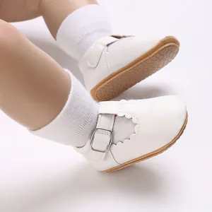 Detailed view of white faux leather baby shoes with scalloped edges and buckle strap.