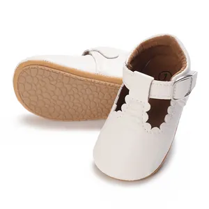 Detailed view of white baby Mary Jane shoes featuring soft rubber non-slip soles and scalloped edges.
