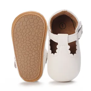 Macro view of white baby walking shoes showing soft non-slip rubber sole and T-strap
