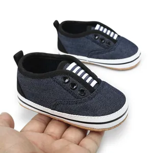 Close-up of blue denim baby walking shoes held by hand for size reference