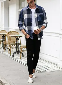 Full detail view of men's blue plaid flannel shirt styled with casual layers outdoors