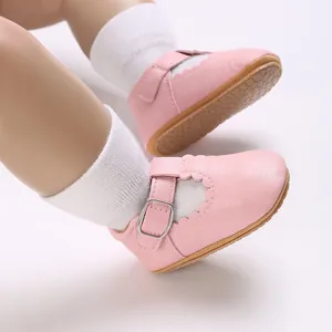 Close-up of pink baby walker shoes with scalloped edges and soft rubber soles for infants.