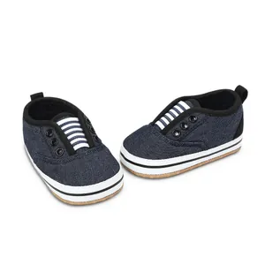 Detailed view of dark blue denim baby walking shoes with white striped elastic bands.