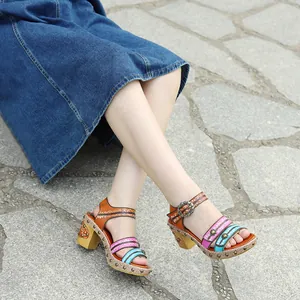 Detailweergave van handgemaakte kleurrijke leren sandalen met retro klinknagels en blokhak