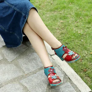 Retro handmade leather sandals with cutout floral design on model legs in outdoor setting