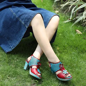 Macro detail of retro leather hollow-out high-heel sandals with floral decor in grass. (90 chars)