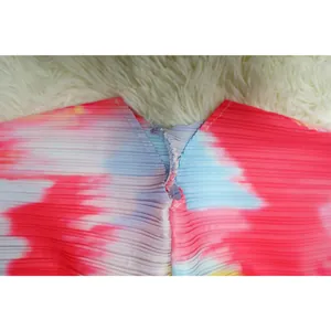 Detalle de cerca que muestra la tela plisada y el estampado tie-dye del vestido en V.