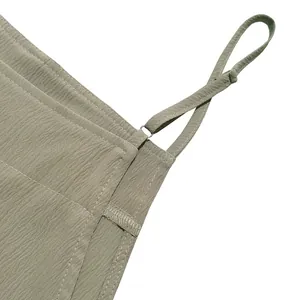 Macro view of adjustable spaghetti strap and fabric texture on this green jumpsuit.