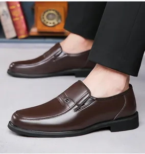 Primo piano di scarpe eleganti da uomo in pelle marrone indossate con pantaloni neri.