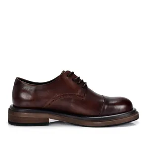 Detalle lateral de zapatos Derby de cuero marrón vintage para hombre con puntera y suela.