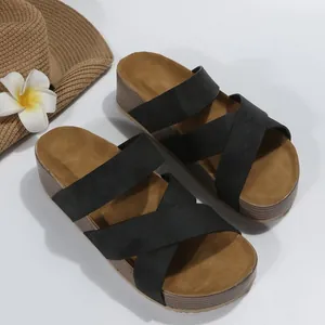 Close-up of black cross-strap platform sandals on white background with summer straw hat