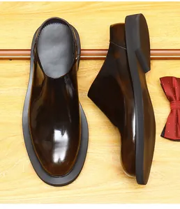 Detail view of burnished shiny leather mule shoes with thick black soles on wood