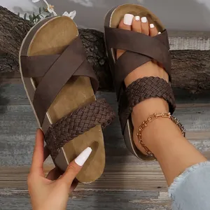 Detail of brown platform sandals with braided strap and cross straps on rustic wood