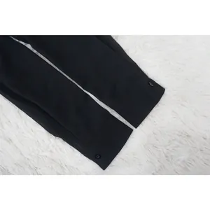 Primer plano de los puños de una camisa de gasa negra con detalles de botones negros.