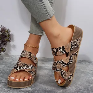 Detailed view of women's platform sandals with crossover snake print straps on model
