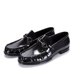 Vista detallada de elegantes mocasines de charol negro con bocado metálico para hombre