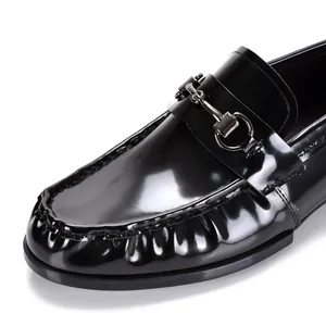 Primer plano de mocasines de charol negro con detalle de bocado metálico clásico elegante.
