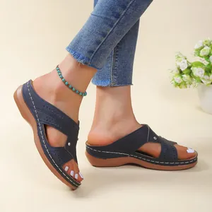 Casual navy blue wedge sandals with white stitching and hollow-out detail on foot