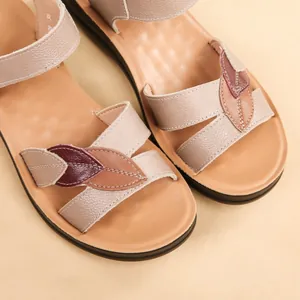 Close-up detail of women's flat leather sandals with colorful leaf pattern on the straps