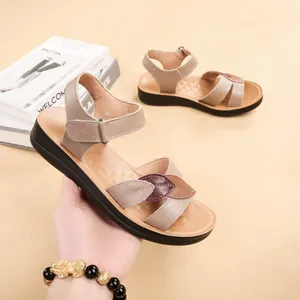 Detail view of brown genuine leather sandals for women with soft sole and leaf decor.
