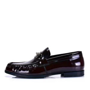 Detalle de elegantes mocasines de charol burdeos para hombre con adorno de bocado dorado