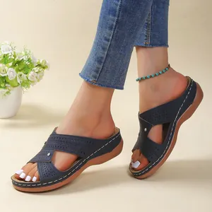 Detailed view of navy blue wedge sandals featuring white contrast stitching and perforations