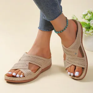 Close-up detail of beige hollow-out wedge sandals with stitching and platform sole.