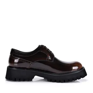 Gedetailleerd zijprofiel van bruine lakleren herenbrogues met dikke profielzolen.