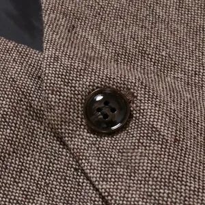 Détail en gros plan du tissu à chevrons marron et d'un bouton de gilet pour homme