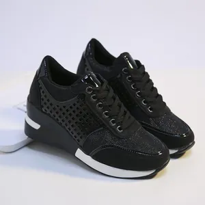 Detalle de zapatillas de cuña negras con acabados brillantes y tejido de purpurina