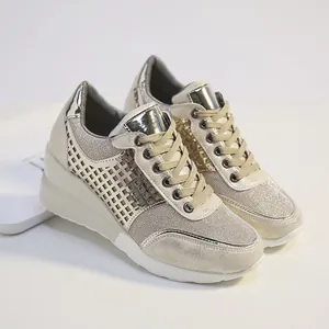 Vista detallada de zapatillas de cuña doradas con paneles de malla y toques metálicos.