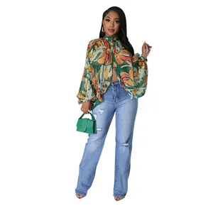 Dettaglio di una blusa in chiffon a fiori con maniche a lanterna e jeans blu denim