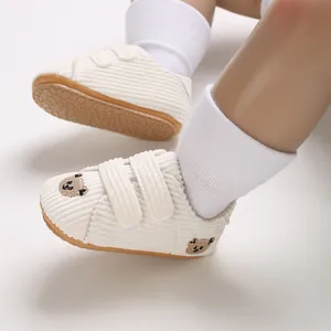 Detalle de zapatos de bebé para caminar en pana blanca con bordado de oso infantil