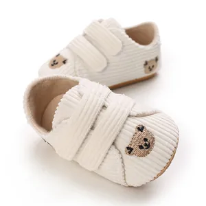 Gros plan de chaussures de bébé en velours côtelé blanc cassé avec motif d'ours brodé
