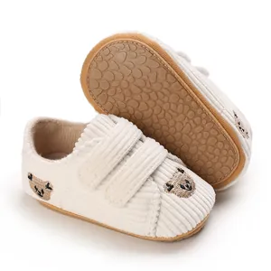Détail des chaussures bébé en velours blanc avec broderie ours et semelles antidérapantes