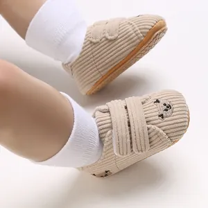 Gros plan de chaussures bébé en velours côtelé avec une broderie d'ours et scratch